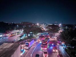 a visão noturna do tráfego da cidade visto ponto de ônibus e vários outros veículos foto