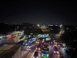 visão noturna do tráfego da cidade visto ponto de ônibus e vários outros veículos foto
