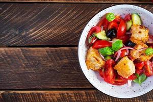 Panzanella toscana de salada italiana tradicional com tomate, pão e azeitonas em conserva foto