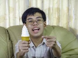 garoto da ásia segure sorvete de baunilha no cone de waffles feliz sorrindo e comendo deliciosamente no verão com se divertir e bom humor. foto