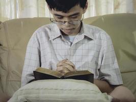 jovens asiáticos oram pela bênção de Deus para desejar ter uma vida melhor com as mãos na bíblia na igreja cristã. e orando na sala de culto. de mãos dadas em oração na Bíblia. foto