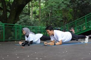 casal jovem asiático saudável exercitando e fazendo prancha juntos no parque. conceito de estilo de vida saudável. foto