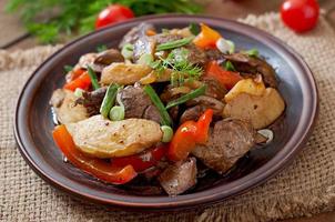 fígado de frango assado com legumes em fundo de madeira foto