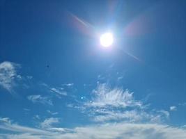 bela vista em raios de sol com alguns reflexos de lente e nuvens em um céu azul foto