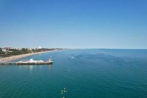 filmagens de alto ângulo e vista aérea do oceano com barcos de alta velocidade, as pessoas estão se divertindo e aproveitando o clima mais quente na frente do mar de bournemouth beach, na inglaterra, reino unido. foto