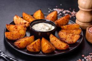 fatias de batata assadas com queijo e ervas e molho de tomate em um fundo escuro foto