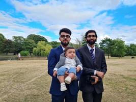 2 jovens machos asiáticos estão andando com um bebê infantil no parque público local de luton inglaterra, reino unido foto