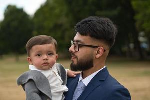 pai paquistanês asiático está segurando seu bebê de 11 meses no parque local foto