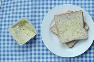 manteiga de alho espalhada em um pão na mesa foto