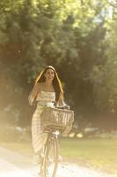 jovem mulher com flores na cesta de bicicleta elétrica foto