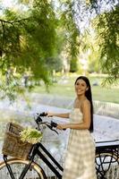 jovem mulher com flores na cesta de bicicleta elétrica foto