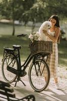 jovem mulher com cachorro branco bichon frise na cesta de bicicleta elétrica foto