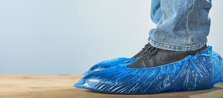 homem com capas de sapato azul usado sobre sapatos clássicos em fundo cinza, closeup. foto com espaço de cópia.