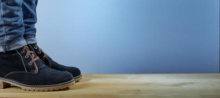 pernas femininas em botas de meia estação e jeans azul no piso de madeira sobre um fundo azul. fundo de moda. foto com espaço de cópia.