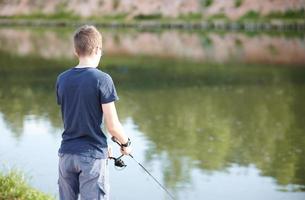 jovem pescando no lago com vara. férias de verão do conceito de estilo de vida de viagens. foto