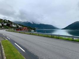 fiordes da noruega ao longo de uma estrada com uma vila à beira da água foto
