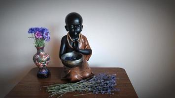 bebê monge, buda, vaso de flor rosa, meditação em casa foto