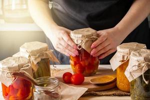 uma mulher fermenta vegetais. tomates em conserva em potes. preservando a colheita de outono. comida orgânica. foto