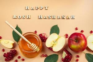 feliz Rosh Hashaná. feriado judaico tradicional ano novo. maçãs, romãs e mel em fundo amarelo. inscrição de letras de madeira. foto