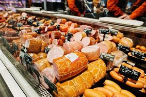 salsichas de leite e várias carnes no supermercado. foto