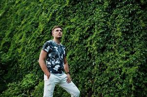 retrato de estilo de vida de homem bonito posando contra a parede de vegetação. foto