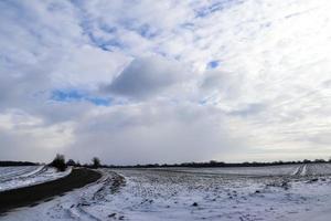 lindas nuvens no céu olhando sobre um campo agrícola coberto de neve. foto