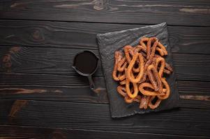 churros caseiros com chocolate em um fundo rústico de madeira escuro. foto