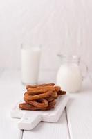 churros caseiros com leite e creme em um fundo branco de madeira. foto