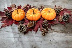 decoração festiva de outono de abóboras, pinheiros e folhas em um fundo de madeira. conceito de dia de ação de graças ou halloween. composição de outono plana leiga com espaço de cópia. foto