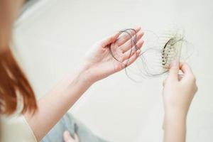 mulher asiática tem problema com perda de cabelo comprido anexado na mão. foto