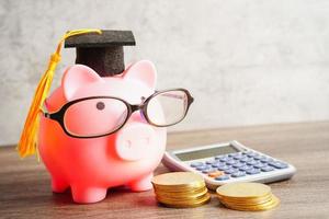 cofrinho usando óculos com moedas e calculadora economizando o conceito de educação bancária. foto