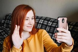 jovem ruiva se comunica online usando smartphone. foto