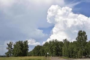 nuvens de trovoada em um dia de verão e uma estrada na zona rural. uma tempestade em um dia claro. foto