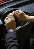 closeup de recém-casados com as mãos no volante, apresentando seus anéis de casamento foto