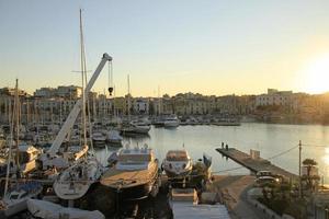 trani, itália - 12 de julho de 2019 - barcos e iates no tranquilo porto de trani em puglia itália, durante o pôr do sol. foto