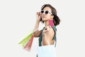 jovem mulher asiática segurando sacola de compras e cartão de crédito branco isolar fundo isolado. Aproveite o conceito de pagamento com cartão de crédito da loja feliz foto