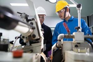 trabalhadores asiáticos do engenheiro de manutenção trabalhando máquinas na fábrica. foto