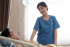 enfermeira asiática falando com paciente na enfermaria do hospital foto