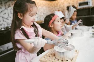 grupo de crianças estão aprendendo a cozinhar biscoito foto