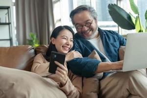 mulher feliz mostrando smartphone para marido na sala de estar em casa foto