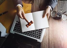 conceito de justiça e direito. juiz masculino em um tribunal com o martelo, trabalhando com, computador e teclado de encaixe, óculos, na mesa na luz da manhã foto