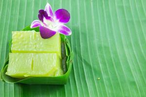 tipo de doce tailandês, bolo doce de várias camadas kanom chan na folha de bananeira com flor de orquídea foto