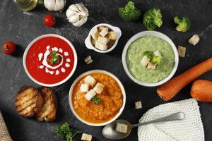 vista superior várias sopas de legumes, brócolis, tomate e, sopa de cenoura com croutons e pão. foto