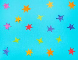 muitas estrelas cortadas de papéis coloridos em papel azul foto