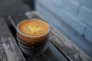 uma xícara de café fica em uma mesa de madeira contra uma parede de tijolos. concentre-se em uma bebida, uma mistura moderna de suco de laranja e um café expresso. foto