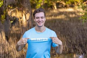 retrato de homem voluntário caucasiano desfruta de trabalho social de caridade ao ar livre no projeto de plantio de mangue foto