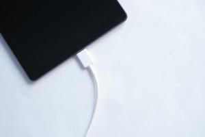 carregando s tablet digital com um cabo em fundo branco foto