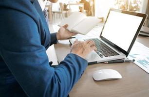 homem de negócios jovem trabalhando com laptop, notas de livro, mãos do homem no computador notebook, empresário no local de trabalho. foto