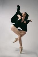 bailarina de bodysuit e jaqueta preta improvisa coreografia clássica e moderna em um estúdio fotográfico foto
