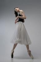 bailarina de bodysuit e saia branca improvisa coreografia clássica e moderna em um estúdio fotográfico foto